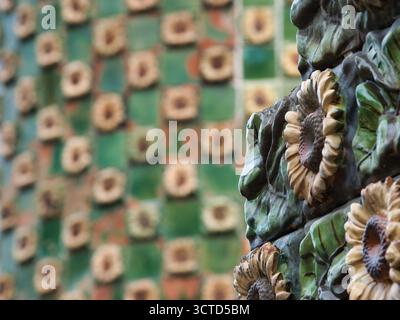 Glazed Ceramic Sunflower Detail Close-up - Macro view of decorative, handcrafted ceramic tile border featuring glossy green leaves and beige sunflower Stock Photo