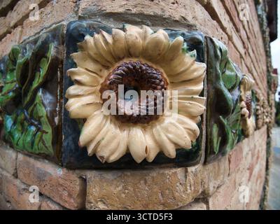 Glazed Ceramic Sunflower Detail Close-up - Macro view of decorative, handcrafted ceramic tile border featuring glossy green leaves and beige sunflower Stock Photo
