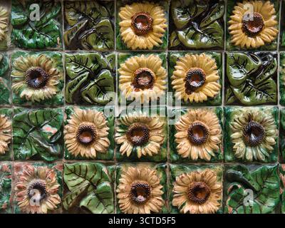 Glazed Ceramic Sunflower Detail Close-up - Macro view of decorative, handcrafted ceramic tile border featuring glossy green leaves and beige sunflower Stock Photo