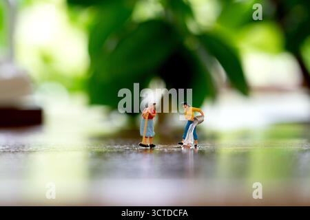 Miniature figurines performing cleaning tasks on a shiny surface Stock Photo