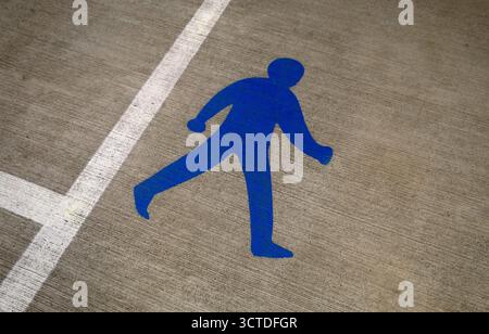 blue painted walking man on car park concrete floor, norfolk, england Stock Photo