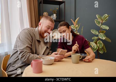Young Man and Young Hispanic Woman Smiling While Using Smartphone Together Stock Photo