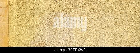 Old painted yellow cement wall. Rough building surface. Colorful grunge background Stock Photo