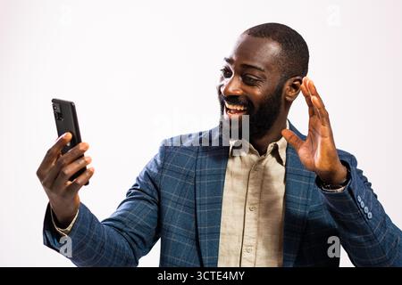 Portrait of happy and successful African-american businessman. Black man in business suit is having video call on smartphone. Stock Photo