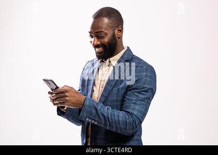 Portrait of happy and successful African-american businessman. Black man in business suit is typing on smartphone. Stock Photo