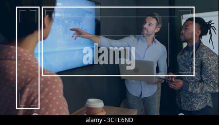 Senior presenter in blue shirt holding laptop presenting data on world map screen at meeting room Stock Photo