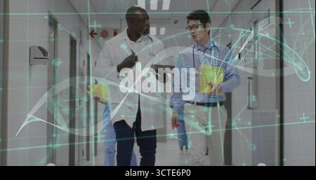 Walking medical team analyzing patient data in hospital corridor, with tablet and DNA hologram Stock Photo