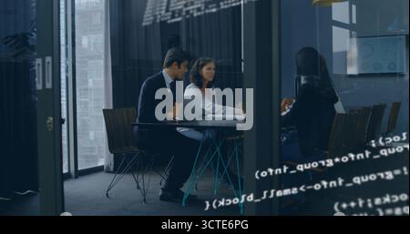 Discussing three suited professionals reviewing laptop and papers in glass room, code reflections Stock Photo
