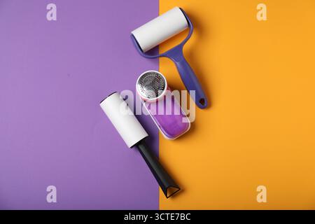 Lint rollers and fabric shaver on color background, flat lay Stock Photo