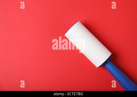 One lint roller on red background, top view. Space for text Stock Photo