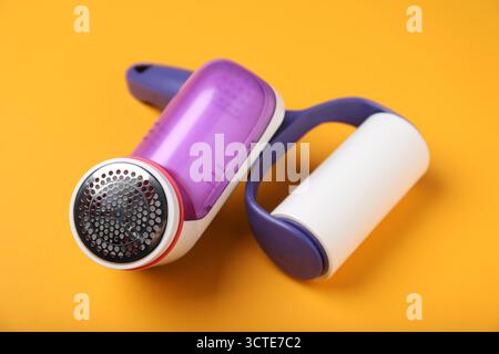 Lint roller and fabric shaver on orange background, closeup Stock Photo