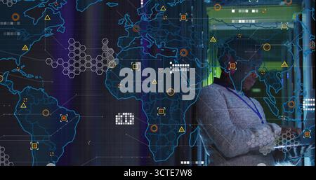 Surveying IT professional wearing gray sweater in data center, with world map display, copy space Stock Photo