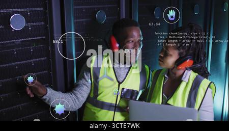 Two technicians wearing vests diagnosing racks in data center aisle, with laptop and data icons Stock Photo