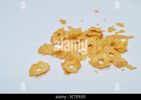 Crispy corn flakes snack scattered on white background, delicious golden yellow cereal chips made from corn Stock Photo