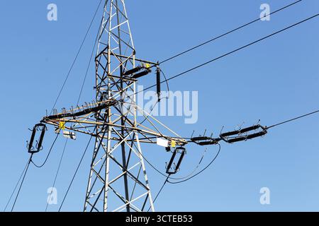 Electricity transmission tower with power cables against blue sky. High voltage structure for energy supply and industrial infrastructure concept. Stock Photo