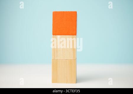 Vertical stacked wooden cubes against a soft blue backdrop, emphasizing simplicity, balance, creativity, and structure. Stock Photo