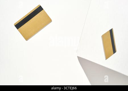 Minimalist composition featuring two gold payment cards on white geometric background. Stock Photo