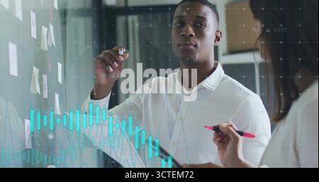 Man in white button-down shirt annotating glass board in office, with sticky notes and graphs Stock Photo