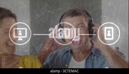 Adjusting over-ear headphones man singing at studio with woman in yellow top, digital network icons Stock Photo