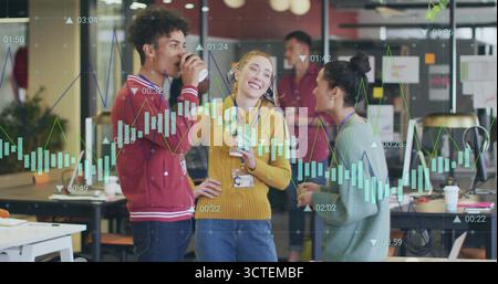Chatting coworkers wearing knit sweaters, sipping coffee in office, featuring smartphone and charts Stock Photo
