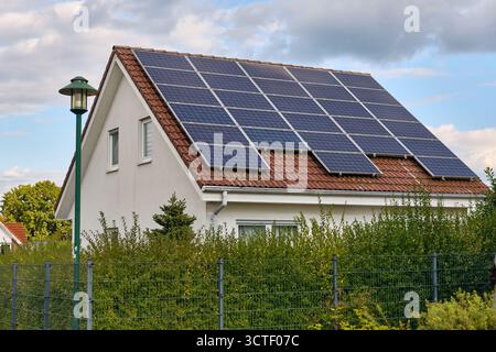 Schiehorn, Germany ; September 30, 2025: White house with red roof fully fitted with solar panels, showing renewable energy use and sustainable living Stock Photo