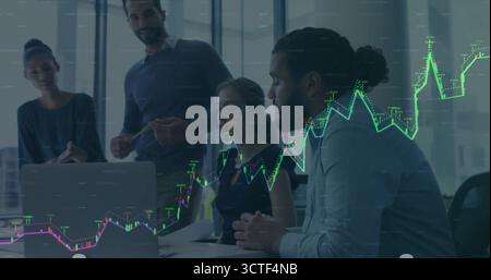 Collaborating business team analyzing financial chart on laptop in glass meeting room, with reports Stock Photo