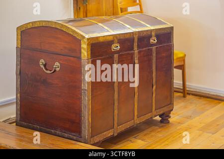 An antique, weathered wooden chest with three drawers secured by metal clasps or locks, potentially containing valuable items Depicted in a vintage se Stock Photo