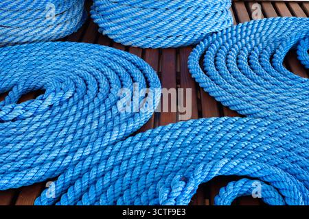 Coiled blue ropes on a wooden deck of the passenger ship Stock Photo