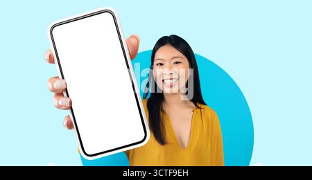 Woman Smiling While Holding a Smartphone Against a Bright Blue Background Stock Photo