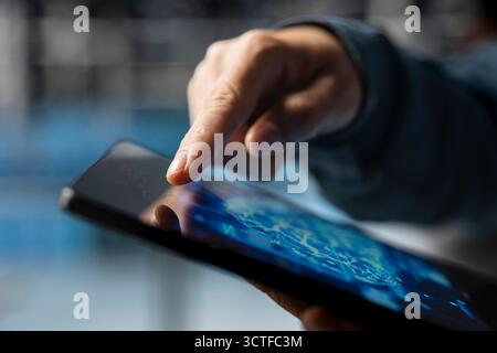 Extreme close up of data center developer using device to do AI algorithms improvements. Programmer in server hub using tablet, maintaining databases supporting AI driven applications. Stock Photo