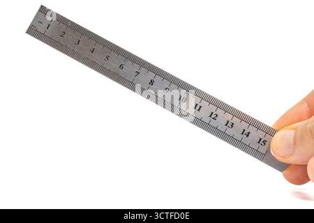 Hand holding a stainless steel ruler on isolated white background. 15cm metal ruler in hand. Precision measuring tool for length and drawing. Closeup Stock Photo