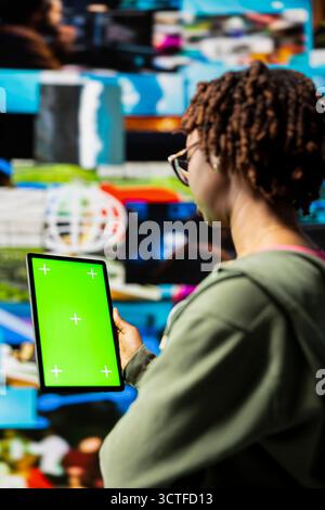 Woman engaging with multimedia dashboards using green screen tablet, showcasing power of technology and digital content. Person having fun interacting with chroma key device apps and internet websites Stock Photo