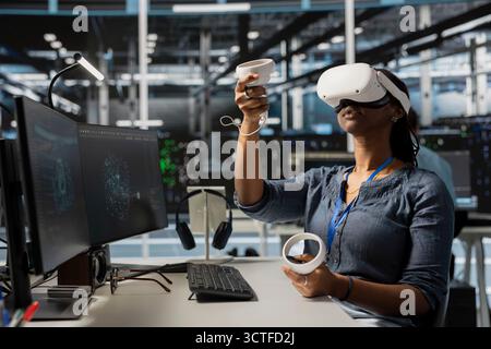 Data center worker wearing VR equipment using artificial intelligence neural networks technology. Server farm admin using virtual reality headset and AI programming language to configure hardware Stock Photo