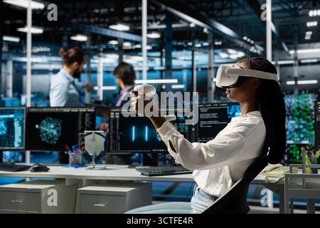 Engineer in data center using virtual reality and AI LLM assistant to do maintenance on equipment rigs. Server hub worker wearing VR headset using large language model chatbot to do backups Stock Photo