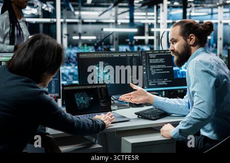 Team of data center admins working on databases supporting AI apps. Teamworking server room colleagues using artificial intelligence technology to do algorithms improvements Stock Photo