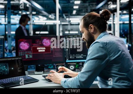 Data center programmer typing on PC keyboard, fixing error warning popup on screen using generative AI. Server hub worker using artificial intelligence chatbot to eliminate glitch alert on monitor Stock Photo