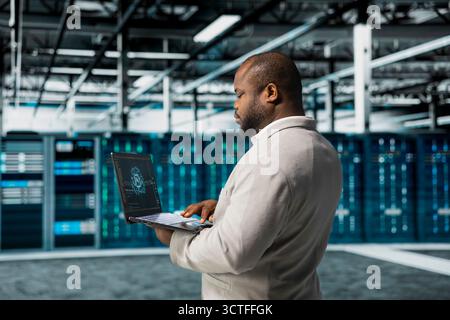 Data center engineer using artificial intelligence automation tools on laptop to increase uptime. Server hub worker working with AI machine learning to accelerate complex AI calculations Stock Photo