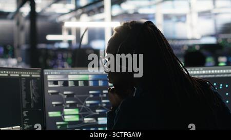 Data center engineer using algorithms to analyze large datasets, putting on headphones. Server farm IT professional using artificial intelligence to recognize data patterns listening music, camera B Stock Photo