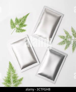 three metal sachets on white background with plants Stock Photo