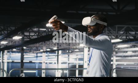 Engineer using VR headset in data center to update server tech, configuring equipment using software tools. Server hub employee reviewing hardware analytics using virtual reality Stock Photo