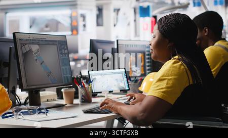 Photovoltaics factory engineer wheelchair user improving solar panels on an industrial software, working on computer for the manufacturing industry. Renewable energy. Camera A Stock Photo
