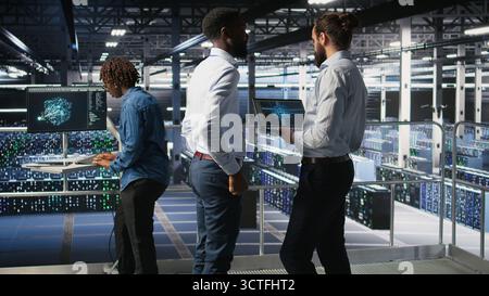 Server farm coworkers doing infrastructure AI machine learning automatization. Data center computer scientists collaborating to maintain servers using artificial intelligence, Stock Photo