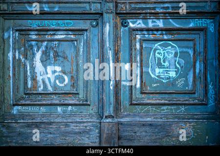 Close-up of a vintage turquoise wooden doorway with graffiti and peeling paint in Prenzlauer Berg, Berlin. Stock Photo