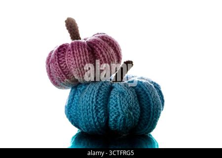 Stacked pink and blue knitted pumpkins made of yarn isolated on white background symbolizing handmade fall harvest and Halloween decoration Stock Photo
