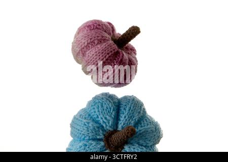A pink knitted pumpkin stacked on a blue one against a clean white background. Soft lighting highlights texture and color contrast for autumn crafts a Stock Photo