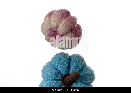 Two handmade yarn pumpkins stacked one over another on white background symbolizing cozy fall mood, knitting creativity and minimalist studio composit Stock Photo