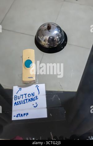wireless doorbell push button and a traditional service bell, with a handwritten note Button assistance-Staff for a customer to request assistance Stock Photo