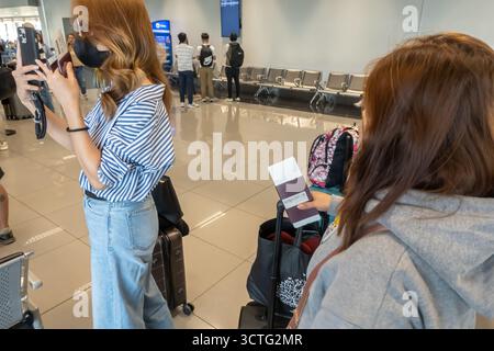 Female travelers holding passport, taking smartphone picture, waiting area, at Ninoy Aquino International Airport (NAIA)  Manila, Philippines Stock Photo