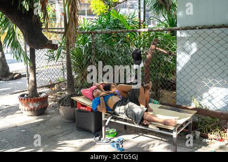 Two people resting on a makeshift bed outdoors, Manila, Philippines Stock Photo