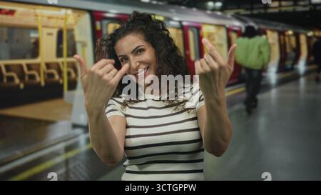 Woman in striped top beckons with hands from open red train door on platform in building; invitation. Stock Photo